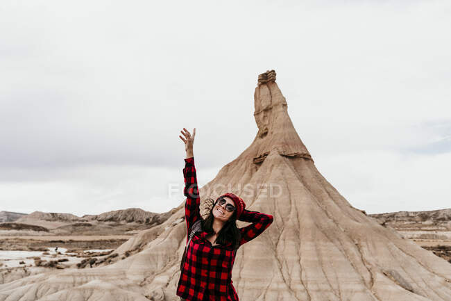 Spanien, Navarra, Porträt einer Touristin, die mit erhobenen Armen vor einer Sandsteinfelsenformation in Bardenas Reales steht — Stockfoto