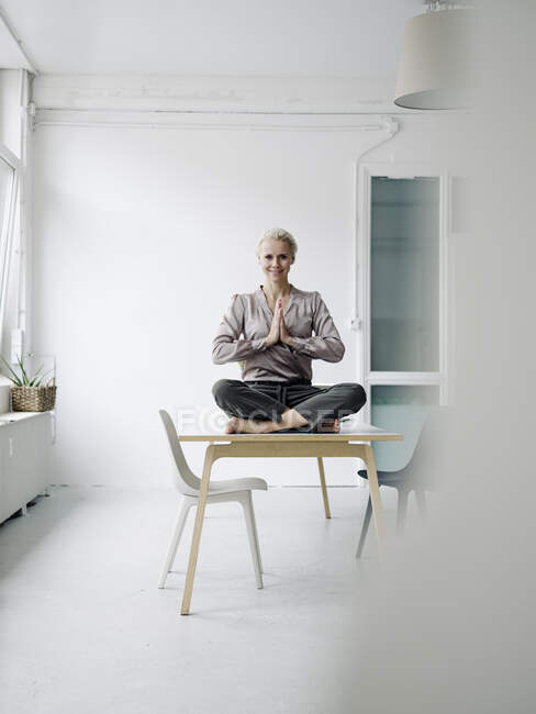 Mujer de negocios meditando mientras está sentada en el escritorio en la oficina - foto de stock