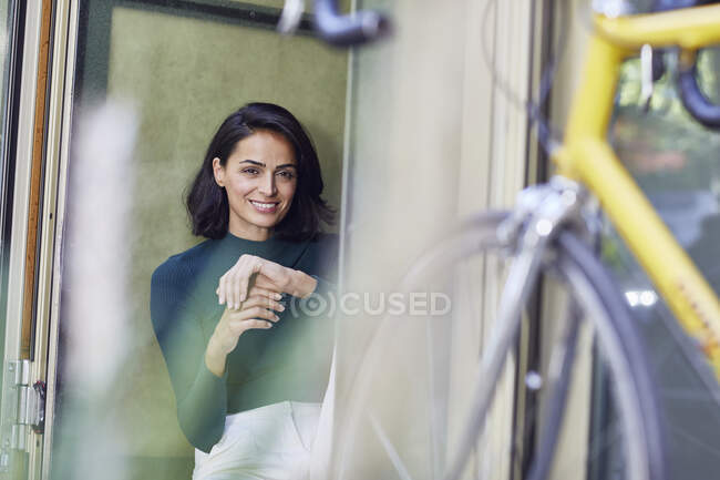 Empresária sorridente sentada à porta do escritório — Fotografia de Stock