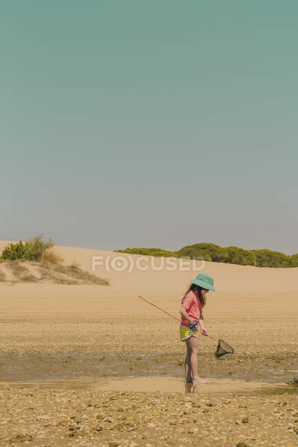 Дівчина у капелюшному крабі на пляжі проти ясного неба в сонячний день. — стокове фото