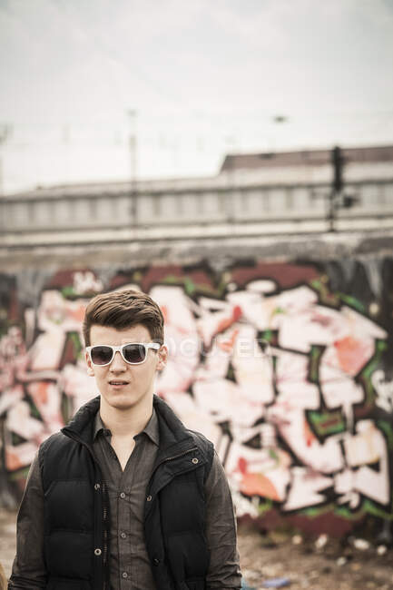 Portrait d'un adolescent portant des lunettes de soleil dans une vieille zone industrielle délabrée — Photo de stock