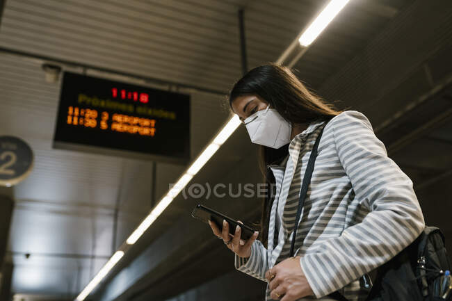 Жіночий пасажир користується телефоном під час очікування на залізничній станції. — стокове фото