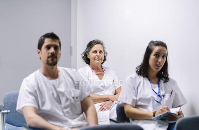 Medici che ascoltano in riunione seduti contro il muro in ospedale — Foto stock