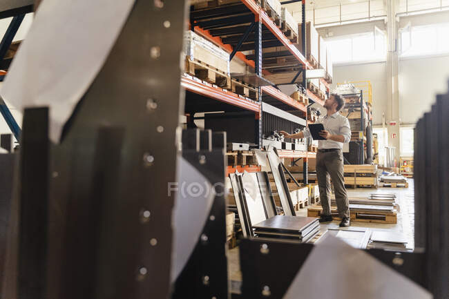 Imprenditore che controlla il materiale del magazzino mentre si trova in fabbrica — Foto stock