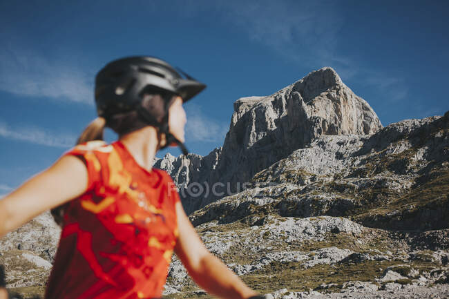 Ciclista donna che osserva la montagna rocciosa nella giornata di sole, Parco Nazionale Picos de Europa, Cantabria, Spagna — Foto stock
