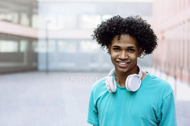 Smiling young man standing with headphones in city — Stock Photo