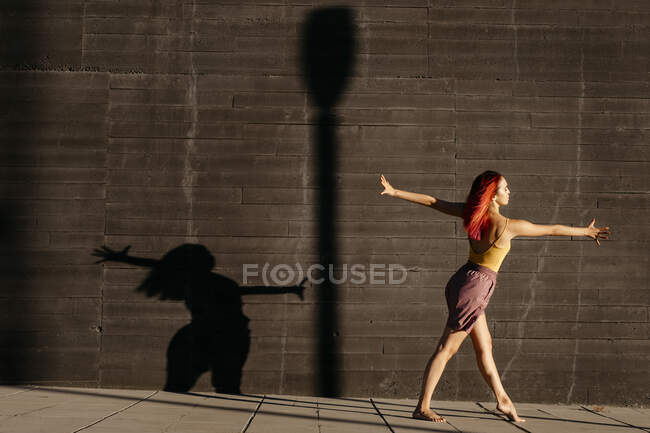 Danse jeune femme casting ombre sur mur noir au coucher du soleil — Photo de stock