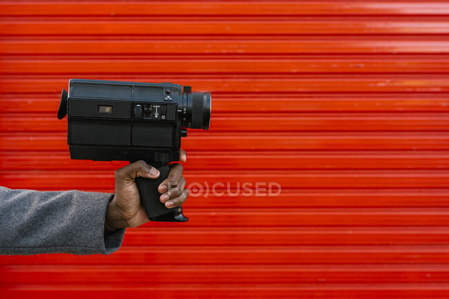 Uomo tenendo vecchia macchina fotografica film contro muro rosso — Foto stock