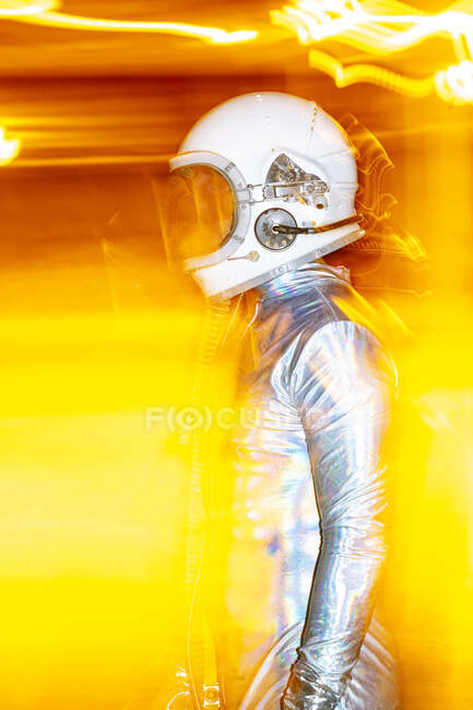 Hombre adulto medio usando traje espacial de pie en medio de la luz abstracta - foto de stock