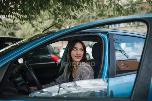 Jovem mulher olhando para longe enquanto sentado no carro — Fotografia de Stock
