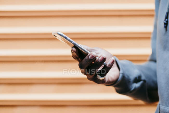 Young man with smart phone by brown corrugated wall — Stock Photo