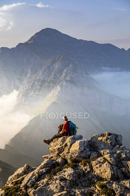 Hombre sentado en la cima del pico de la montaña en los Alpes bergamascos, Italia - foto de stock