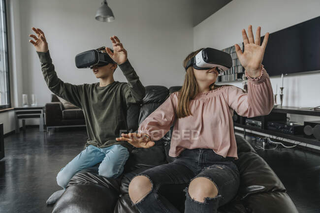 Friends looking through virtual reality simulators while relaxing on couch at home — Stock Photo