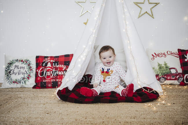 Bambina sorridente mentre gioca in tenda a casa durante il Natale — Foto stock