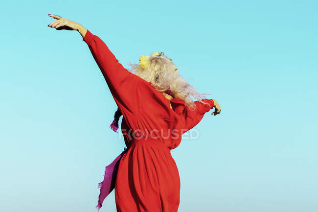Mulher despreocupada com os braços estendidos contra o céu azul no dia ensolarado — Fotografia de Stock
