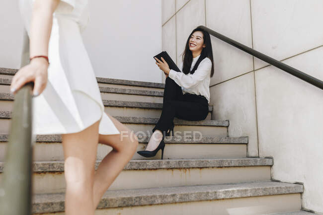 Mujer de negocios de pie cerca sonriente compañero de trabajo en la escalera - foto de stock
