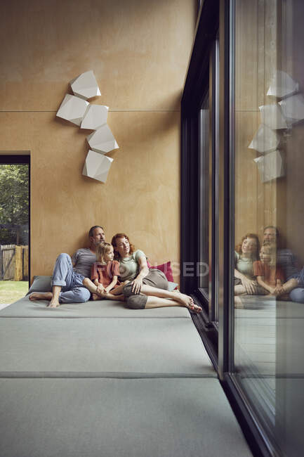 Famille regardant par la fenêtre tout en se relaxant sur le lit à la maison — Photo de stock