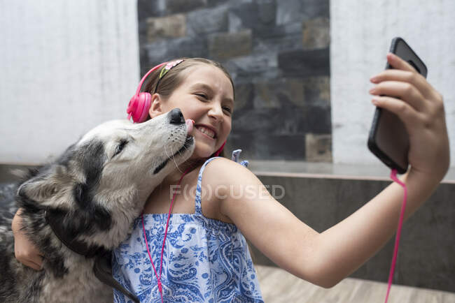 Дівчата беруться за селфі з собакою через мобільний телефон вдома. — стокове фото