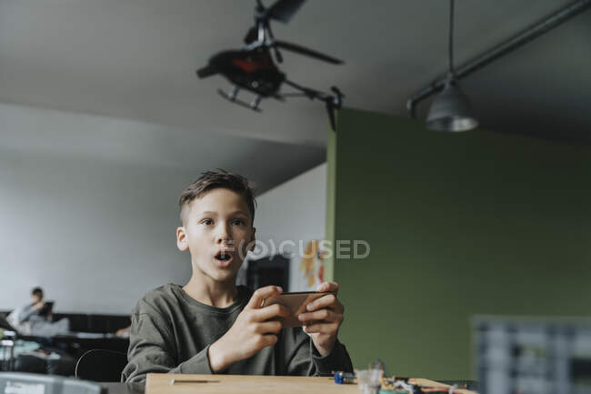 Ragazzo che controlla elicottero in miniatura con un'app — Foto stock