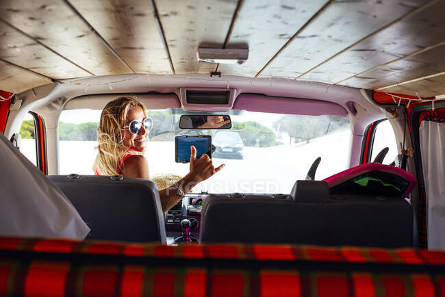 Donna sorridente posa mentre guarda oltre la spalla seduta in furgone — Foto stock