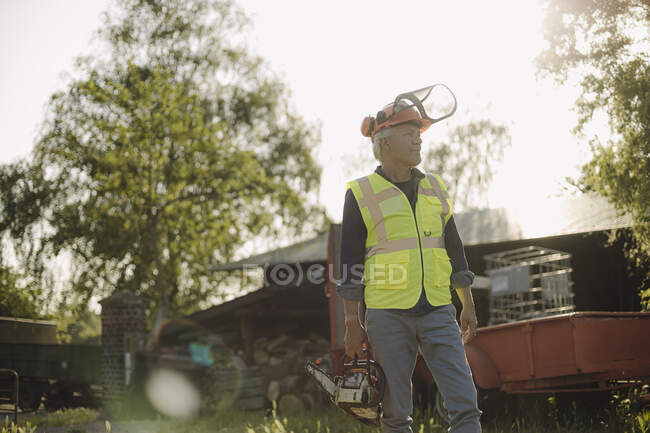 Man with work tool standing against sky in forest — Stock Photo