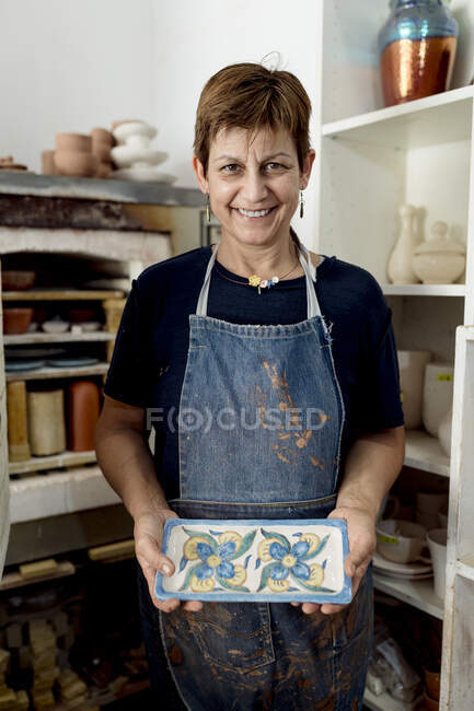 Feliz artista femenina mostrando sus diseños en el taller de cerámica - foto de stock