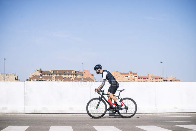 Hombre amputado ciclista montar en bicicleta en el camino contra el cielo azul claro durante el día soleado - foto de stock
