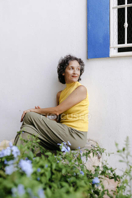 Mature woman looking over shoulder while sitting on concrete bench — Stock Photo