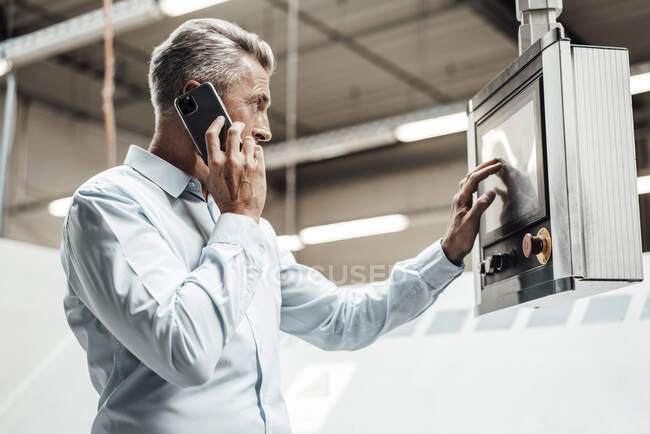 Зрілий чоловік - інженер, який розмовляє по телефону під час роботи на заводі. — стокове фото