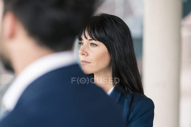 Розсудлива бізнес-леді, яка відвернулася, стоячи серед чоловіків під час зустрічі в офісі — стокове фото