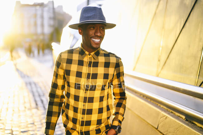 Посмішка африканця в жовтій шовковистій сорочці, що стоїть у місті під час заходу сонця — стокове фото