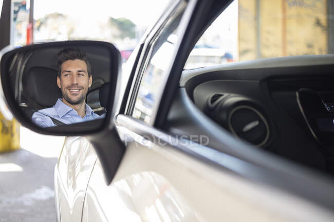 Spiegelreflex des Geschäftsmannes beim Autofahren lächelnd — Stockfoto