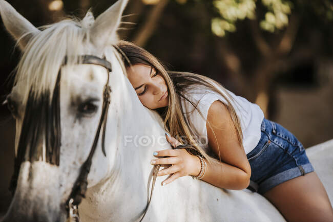 Belle jeune femme penchée sur le cheval blanc — Photo de stock