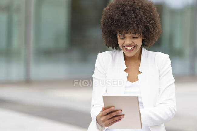 Улыбающаяся деловая женщина, использующая цифровой планшет на открытом воздухе — стоковое фото