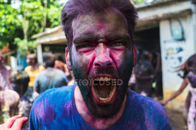 Nahaufnahme eines jungen Mannes mit Puderfarbe im Gesicht, der beim Holi-Festival schreit — Stockfoto