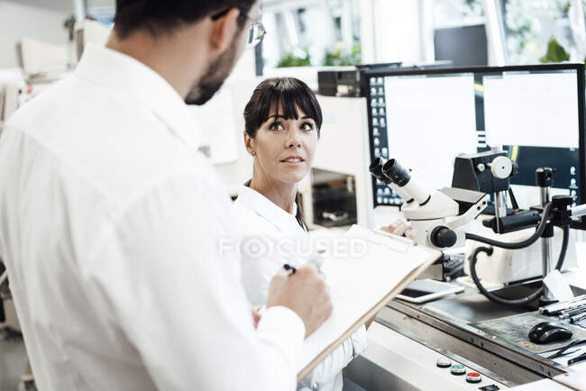 Бизнесмен смотрит на бизнесмена, стоящего с планшетом в лаборатории — стоковое фото
