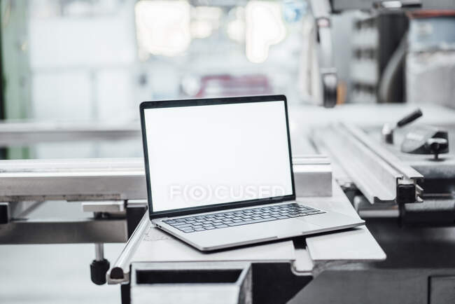 Ordenador portátil con pantalla en blanco en la maquinaria en fábrica - foto de stock