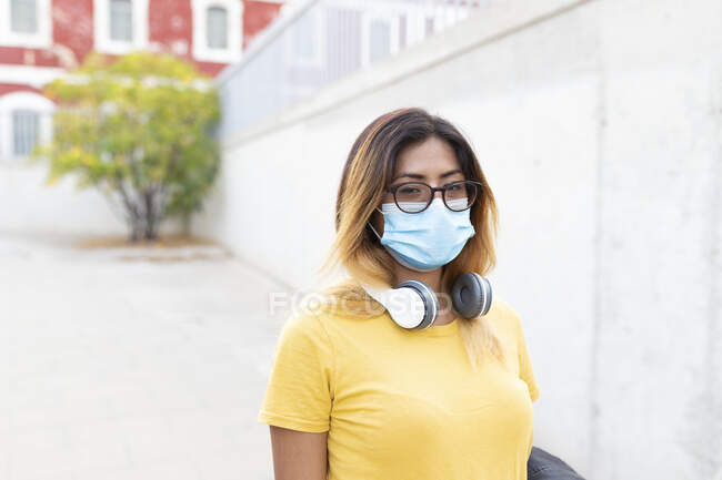 Mujer joven con máscara protectora y anteojos en la parada de autobús - foto de stock