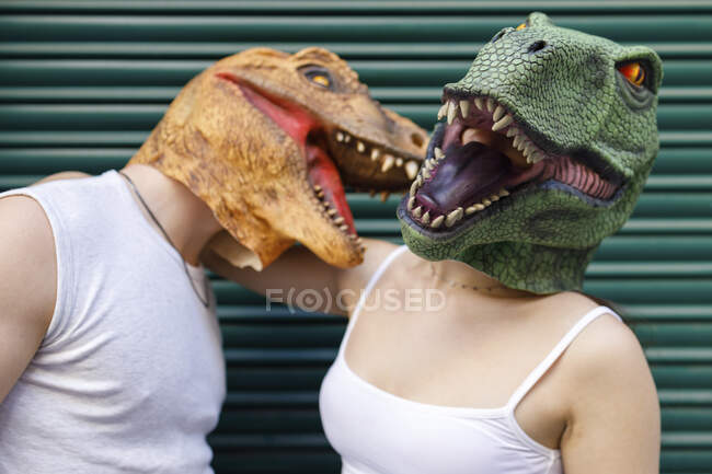 Mascara de dinosaurio masculina y femenina contra obturador metálico verde - foto de stock