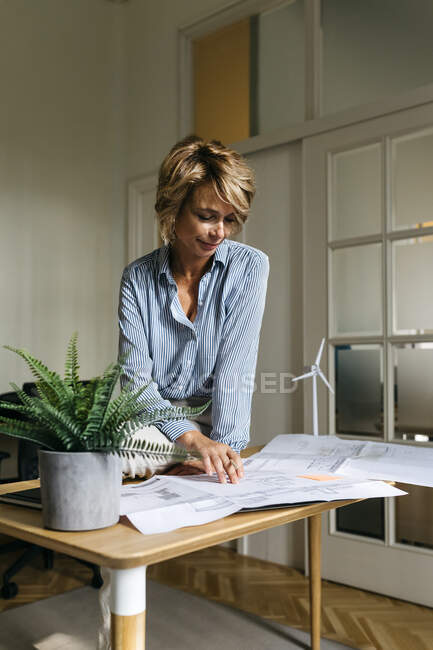 Architetto donna che analizza il progetto mentre è seduta sulla scrivania in ufficio — Foto stock