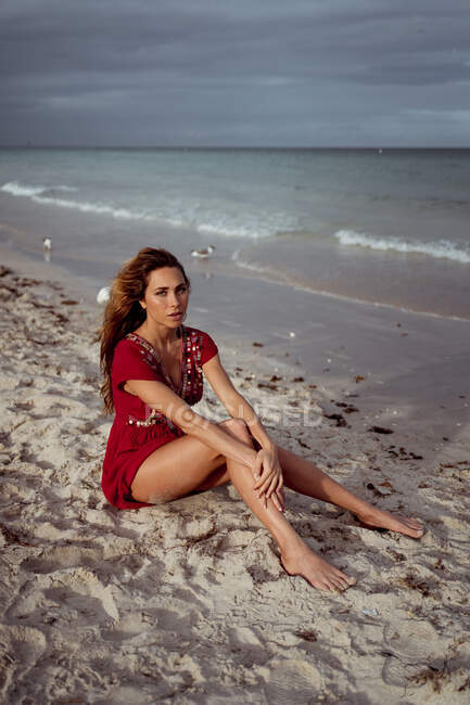 Beautiful woman sitting on shore at beach — Stock Photo