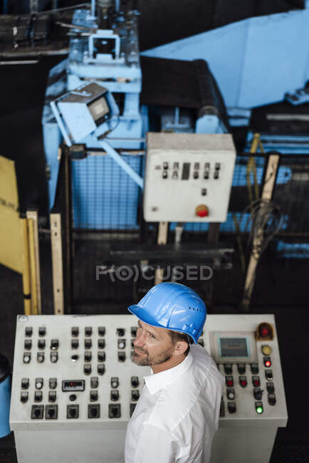 Male owner looking away while standing control panel in factory — Stock Photo