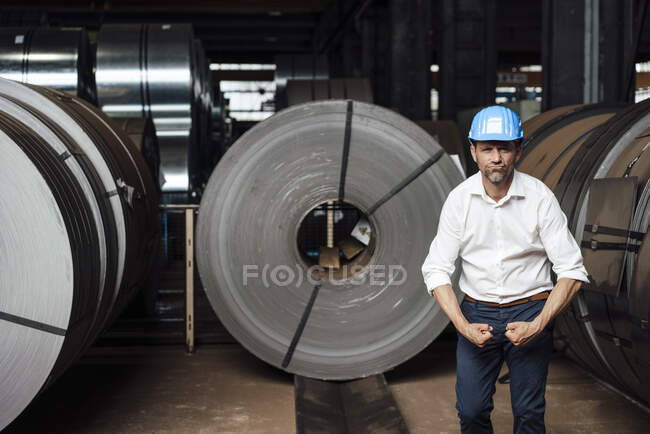 Homme d'affaires flexion des muscles tout en étant debout dans l'usine — Photo de stock