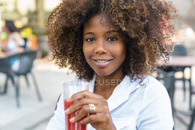 Взрослая женщина пьет сок сидя в кафе на тротуаре — стоковое фото