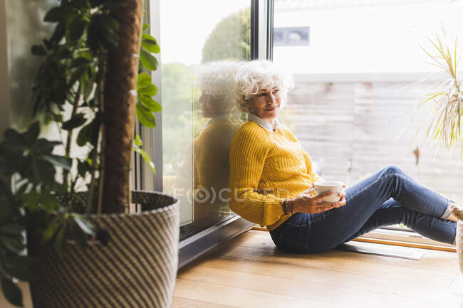 Mulher madura sentada com xícara de café em casa — Fotografia de Stock