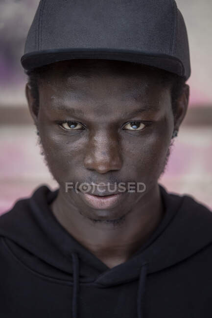 Joven confiado usando gorra de pie contra contenedor - foto de stock