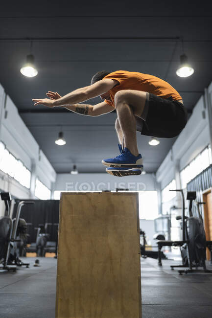 Спортсмен прыгает через деревянную коробку в спортзале — стоковое фото