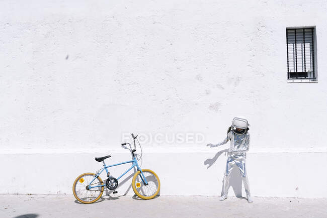 Boy in astronaut costume standing by bicycle on sidewalk in city — Stock Photo