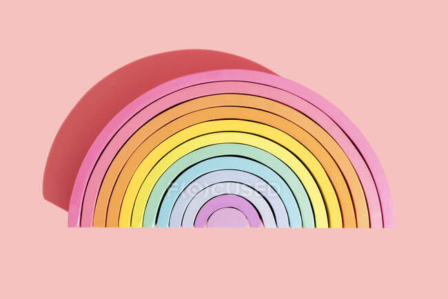 Colorido semi-círculo arco iris juguete sobre fondo rosa - foto de stock