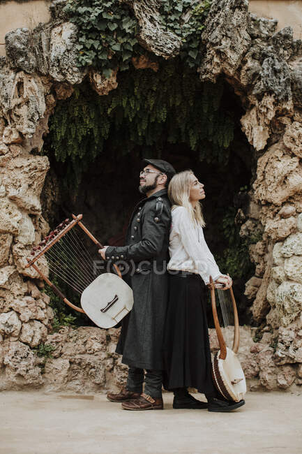Maschio e femmina con strumento musicale lira contro struttura costruita — Foto stock